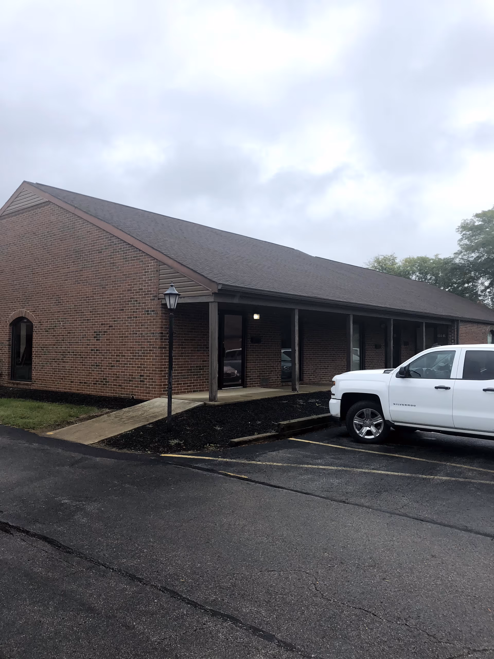 Brick senior living facility with a covered entrance and a white pickup truck parked nearby.