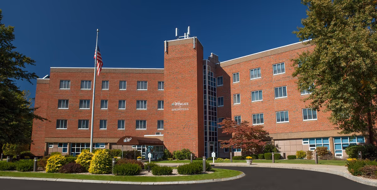 Brick Wingate at Springfield exterior with flagpole, glass entrance, and manicured landscaping.