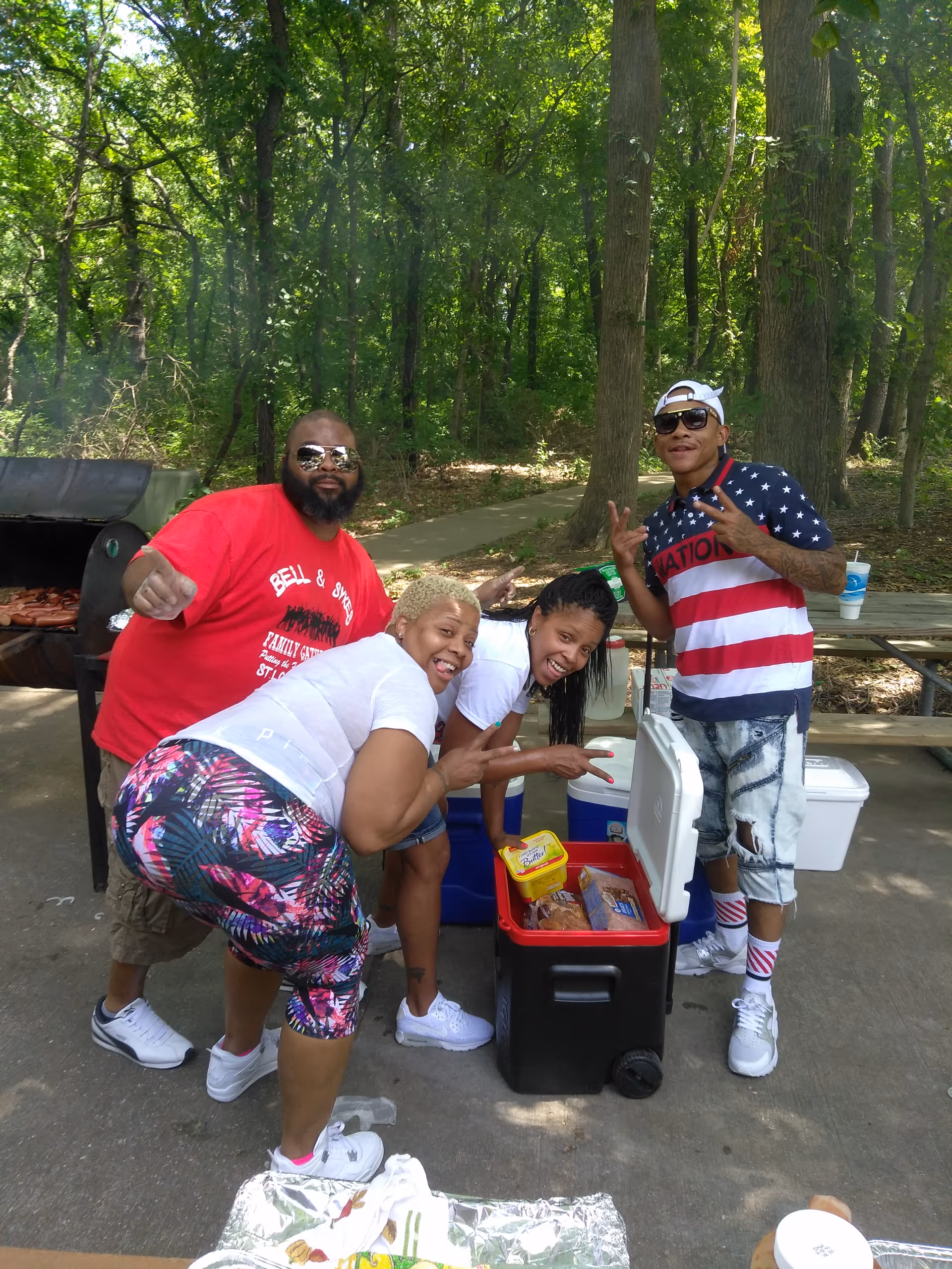 Group of residents enjoying an outdoor barbecue around a cooler and grill.