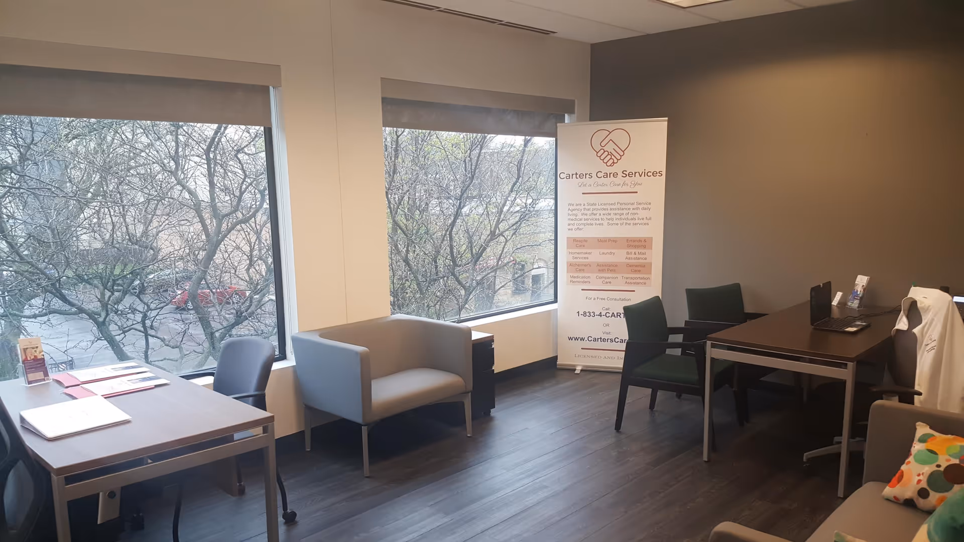 Interior office space with desks, chairs, and a Carters Care Services banner by windows.