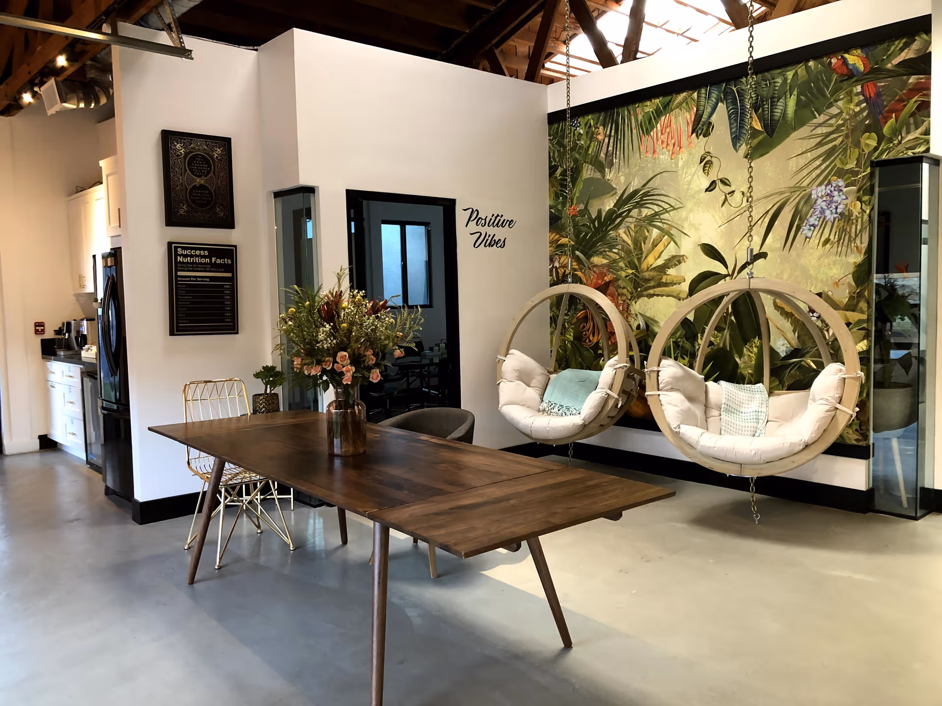 Modern Magnus Care lounge with a wooden table, tropical mural, and hanging circular chairs.
