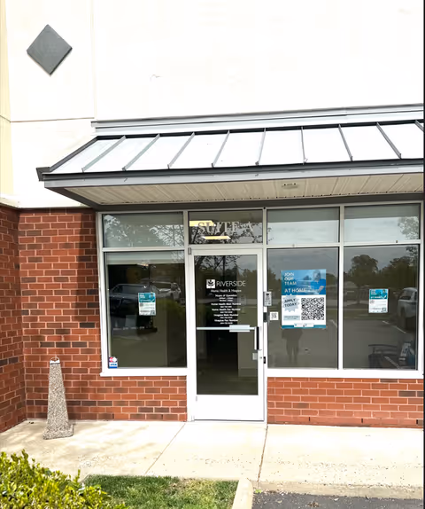 Exterior entrance of Riverside Home Health and Hospice facility with glass doors and brick facade.