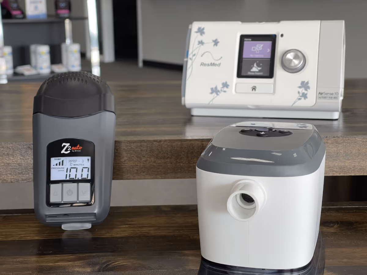 Blood pressure monitor and CPAP device on a wooden counter indoors.