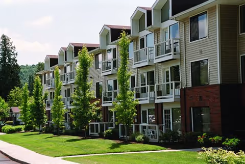 Exterior view of Powell Valley Assisted Living building with balconies, green lawn, and trees.