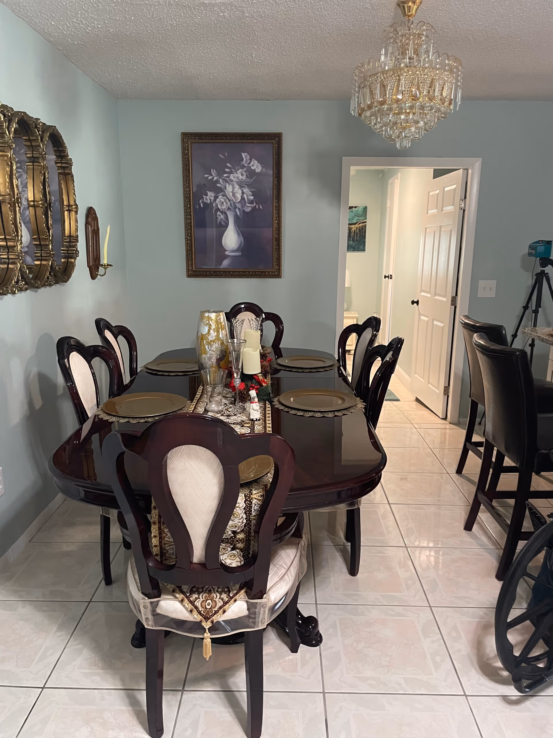 Dining room with a dark wood table, chandelier, and place settings.