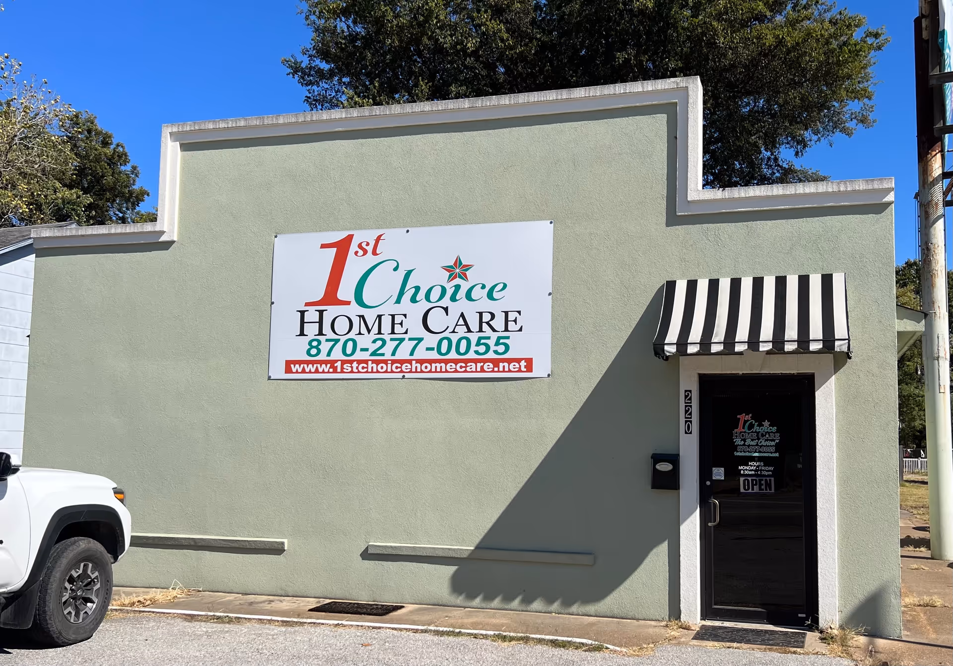 Building front of a 1st Choice Home Care with green wall, sign, and striped awning.