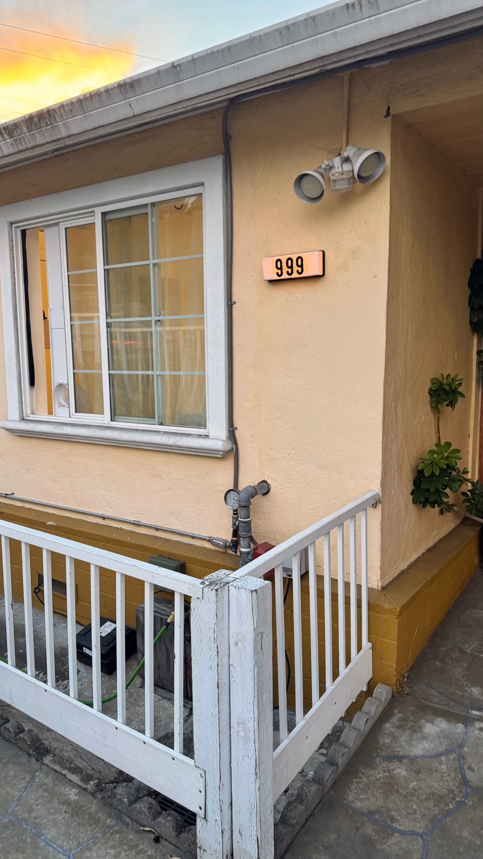 Exterior view of a beige building entrance with white railing and number 999.