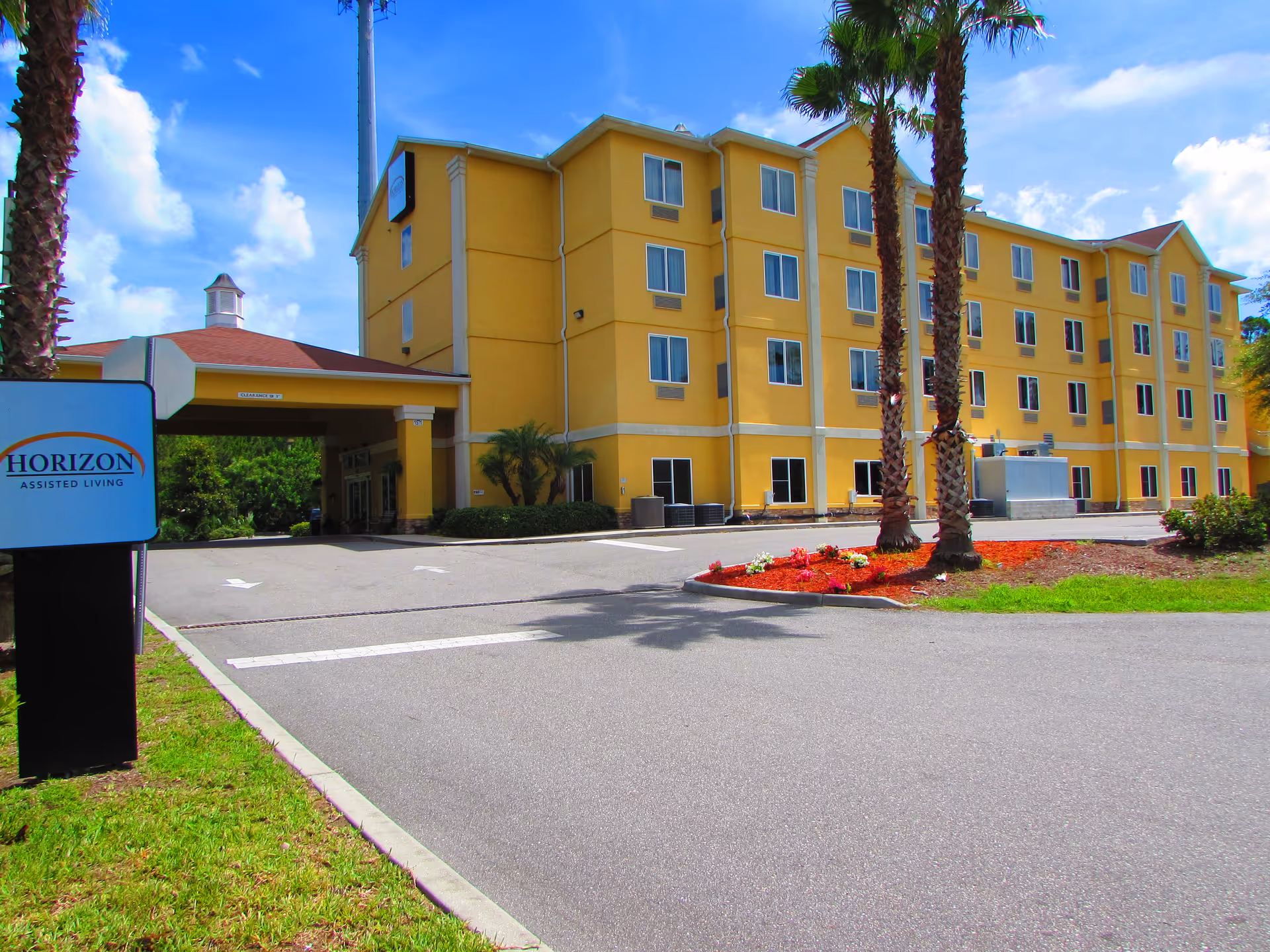 Exterior view of Horizon Assisted Living facility with driveway and palm trees.