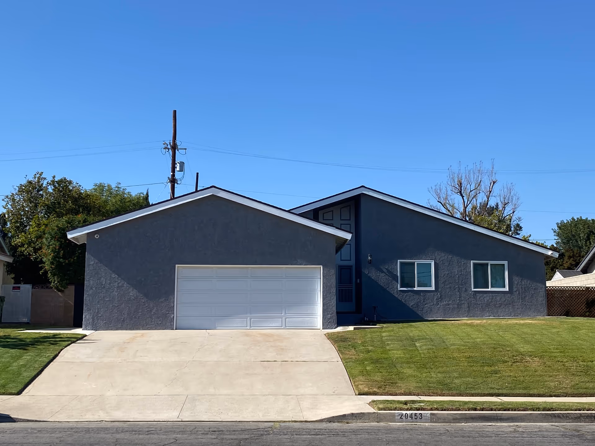 Grey modern house-style building with a two-car garage and manicured lawn.