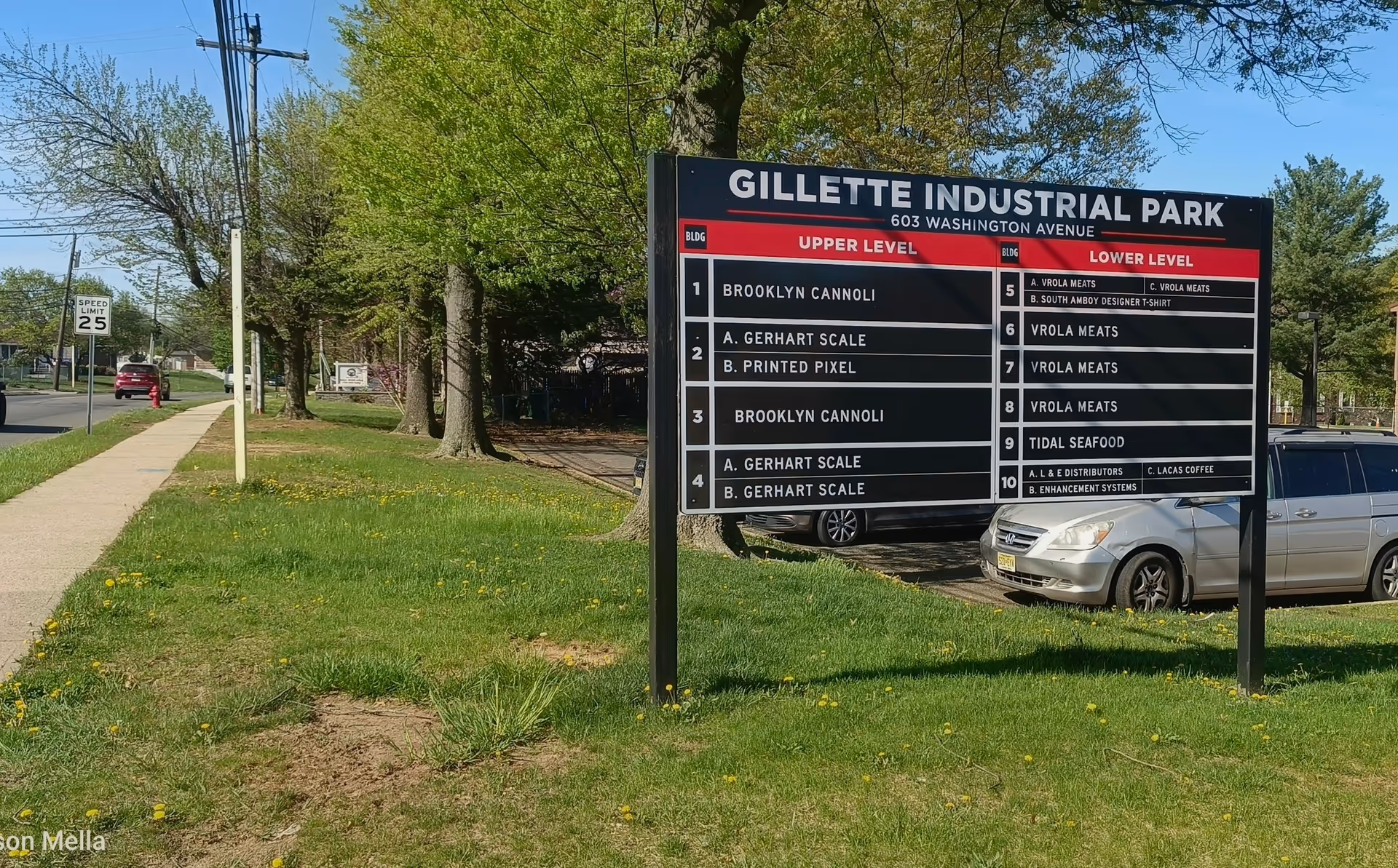 A large Gillette Industrial Park sign on a grassy lot beside a sidewalk.