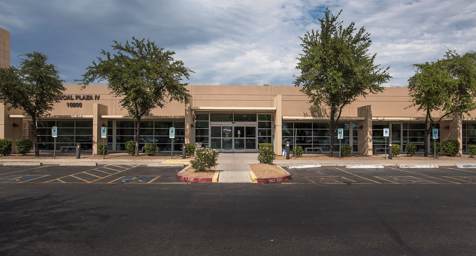 Facade of a single-story medical building with glass entrance and parking lot.