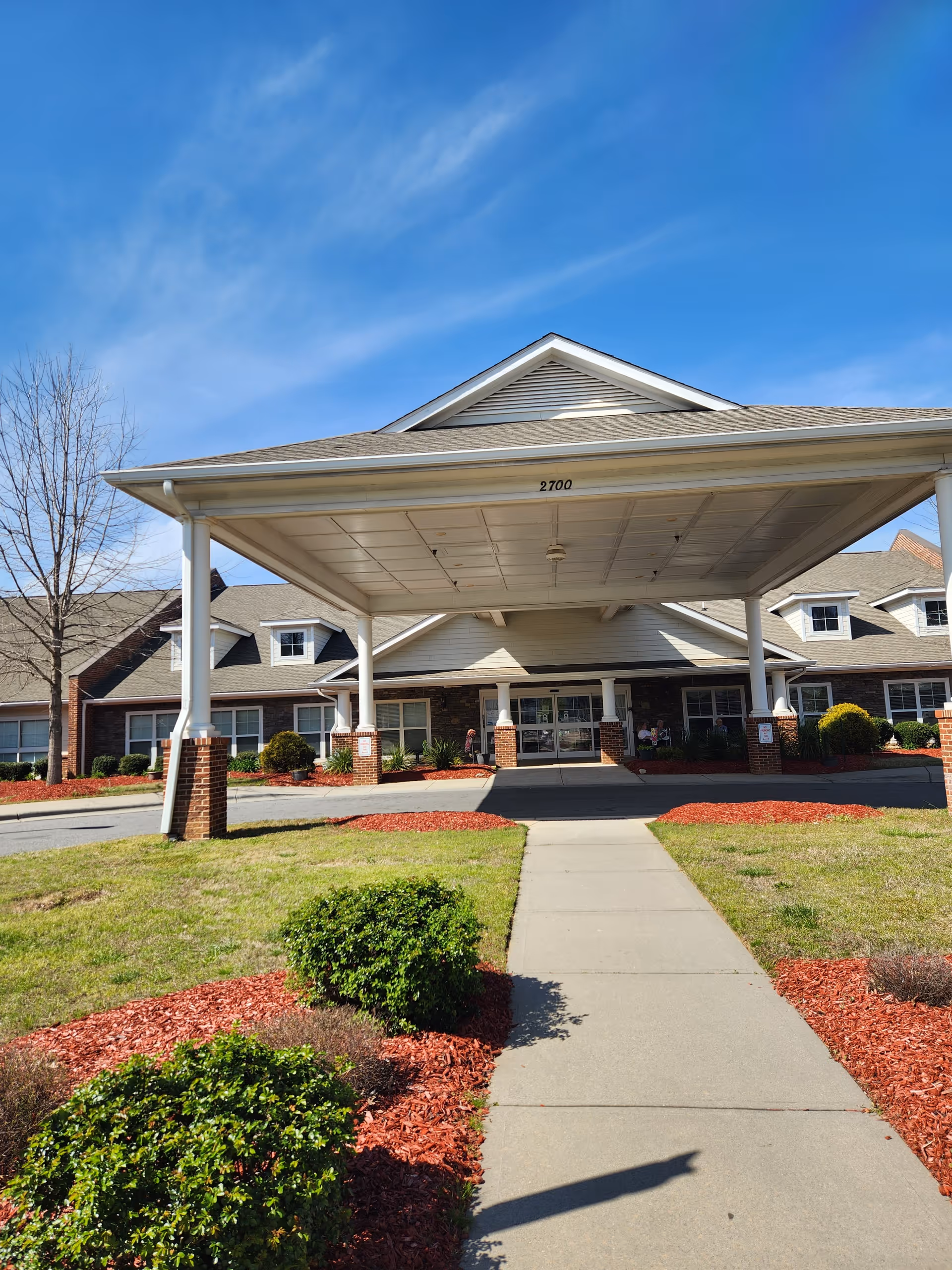 Exterior view of a senior living facility entrance with a covered drop-off area.