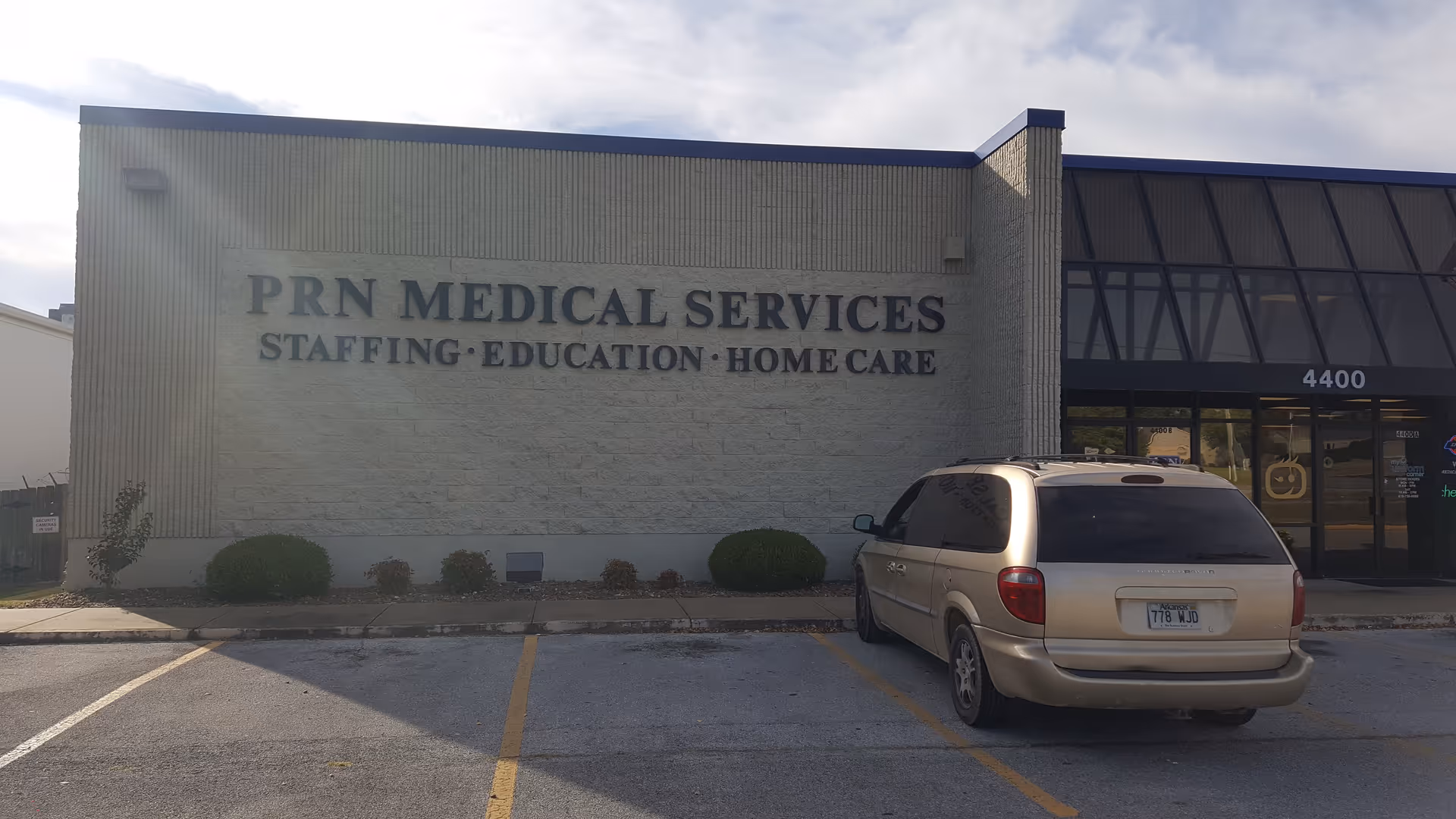 A medical services facility exterior with a beige minivan parked in front.