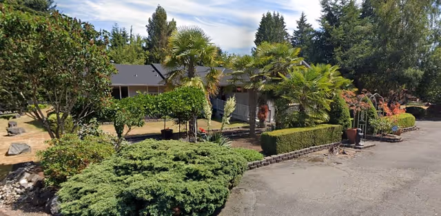 Exterior view of Golden Age 3 senior living facility with landscaped shrubs and a driveway.