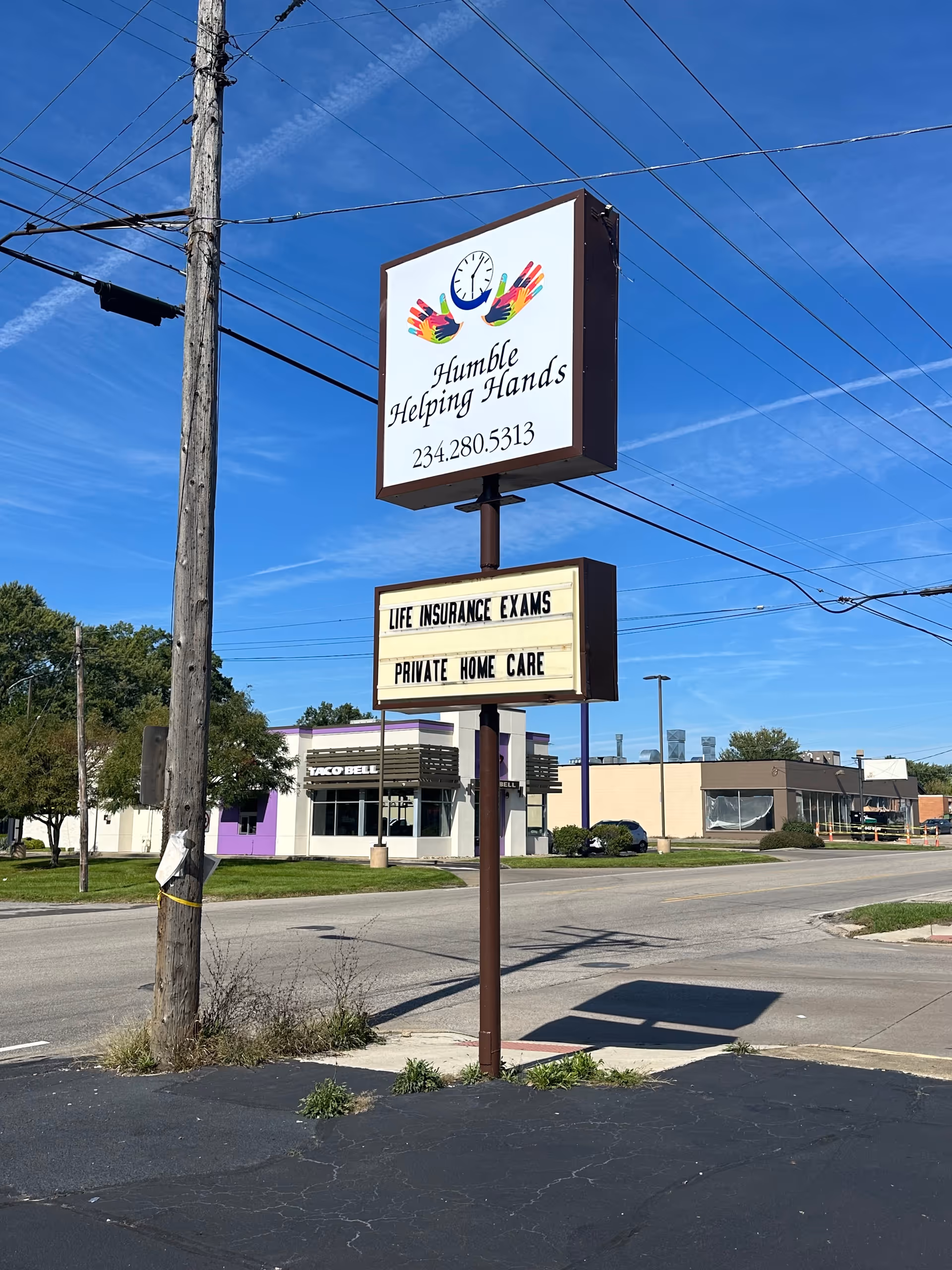 Exterior street scene with Humble Helping Hands LLC sign and nearby storefronts.