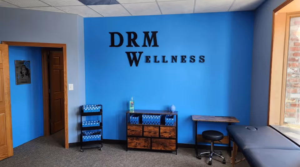 Blue wall with DRM Wellness sign, cabinets, and a desk in a small interior space.