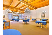 Dining room at Skyline Transitional Care Center with blue tablecloths, chandeliers, and wooden beams.