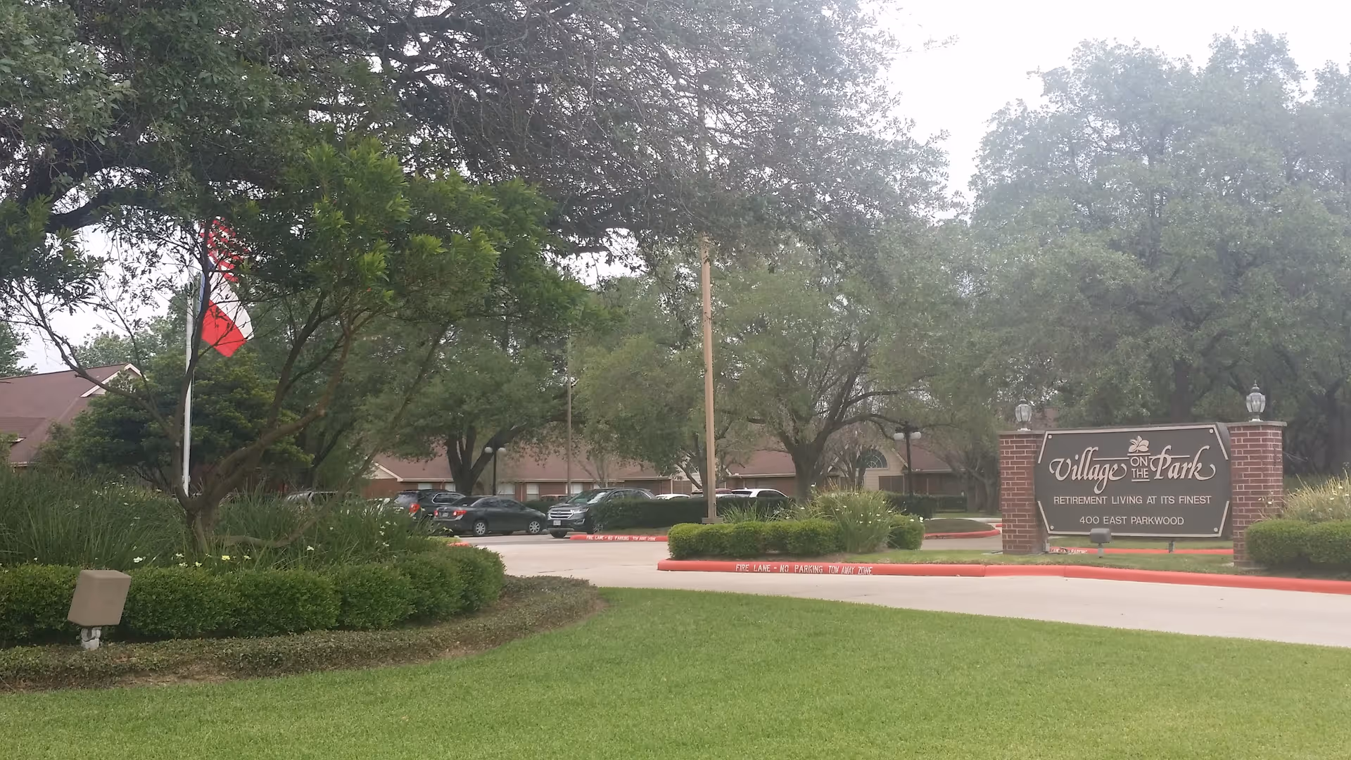 Exterior view of Village on the Park Friendswood entrance sign and parking lot