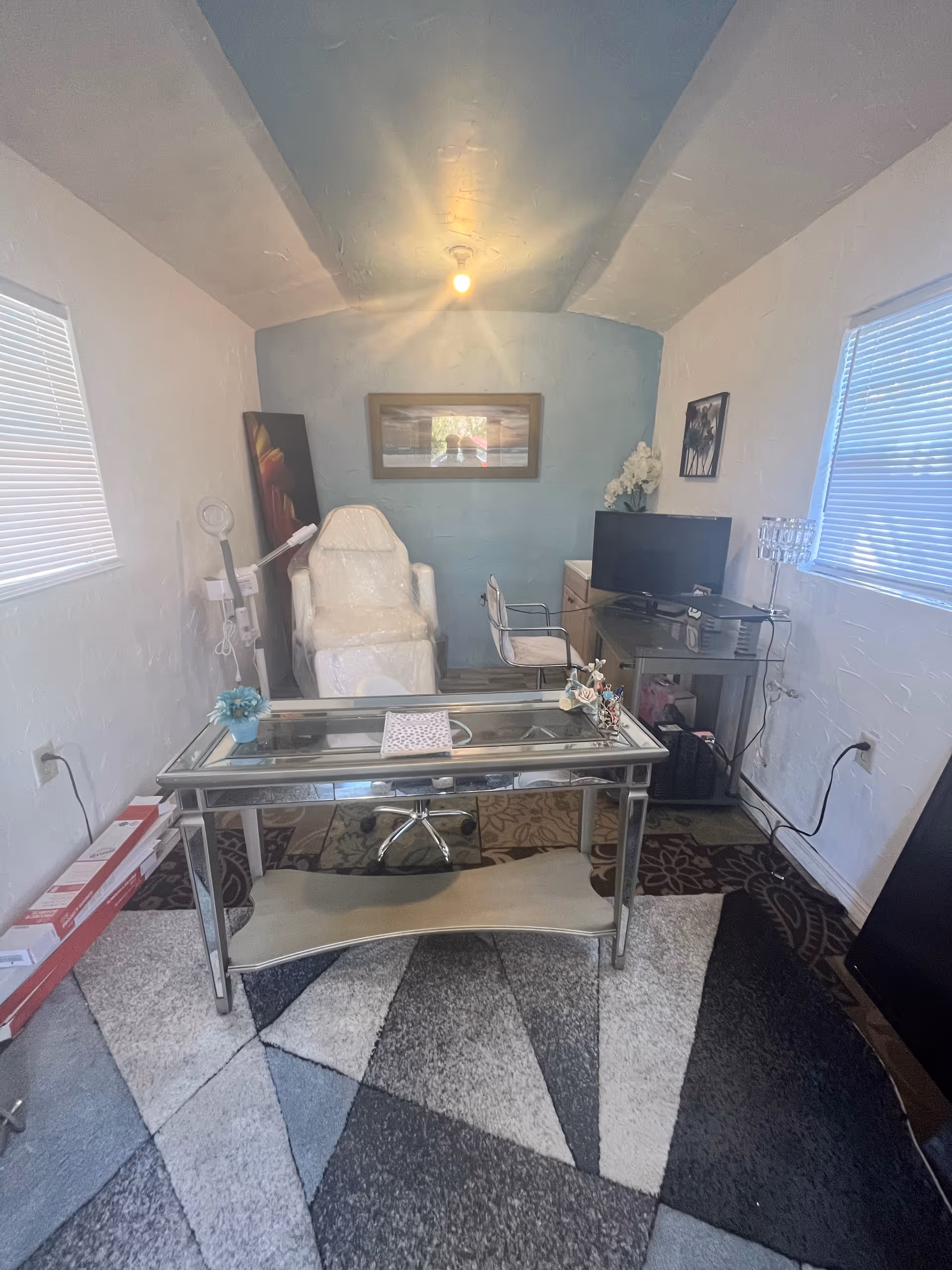 Small interior office/treatment room with glass desk and reclining chair
