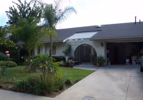 Front view of a single-story senior living home with arched entry and landscaping.
