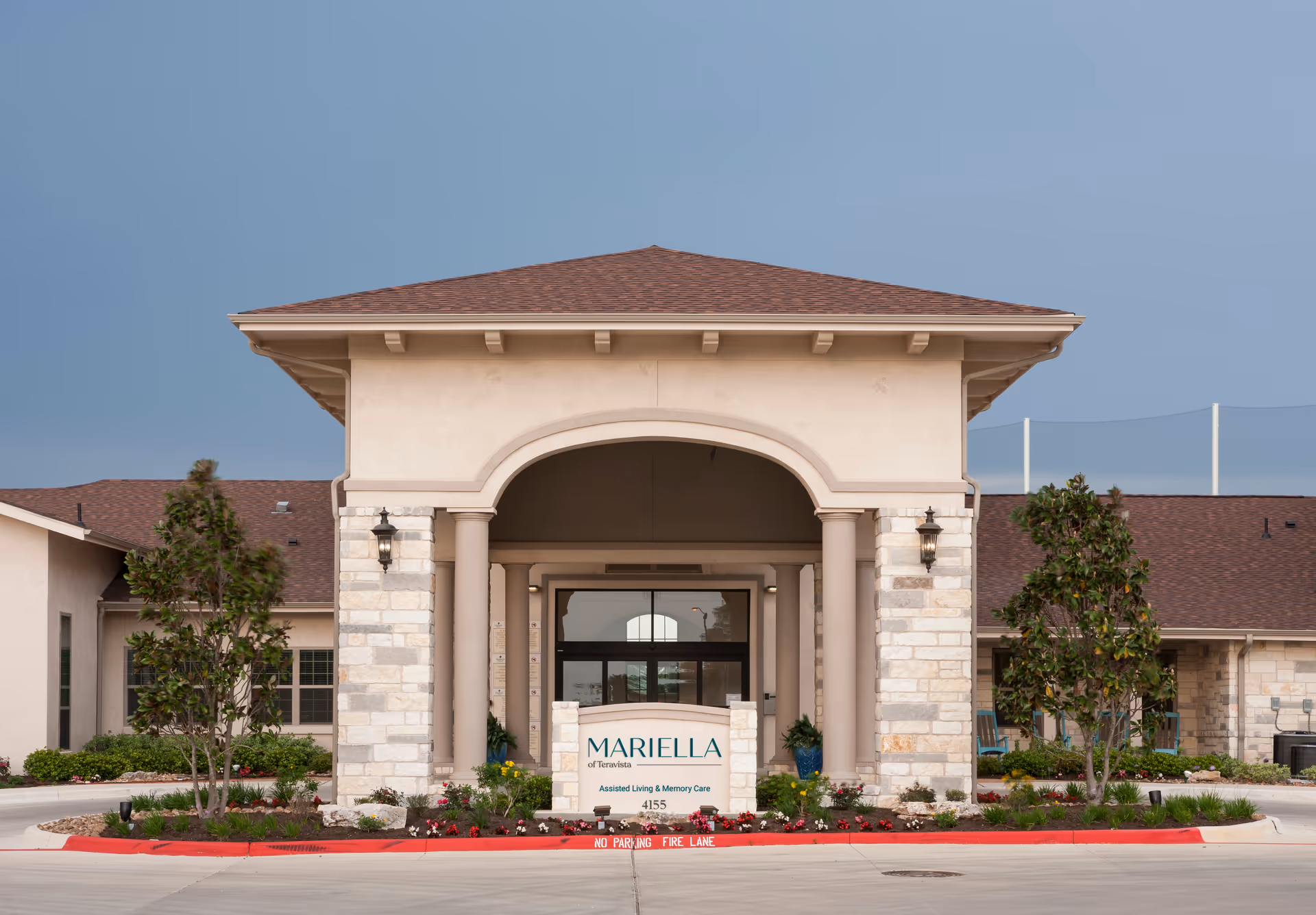 Front entrance of a senior living facility with arched doorway and stone columns.