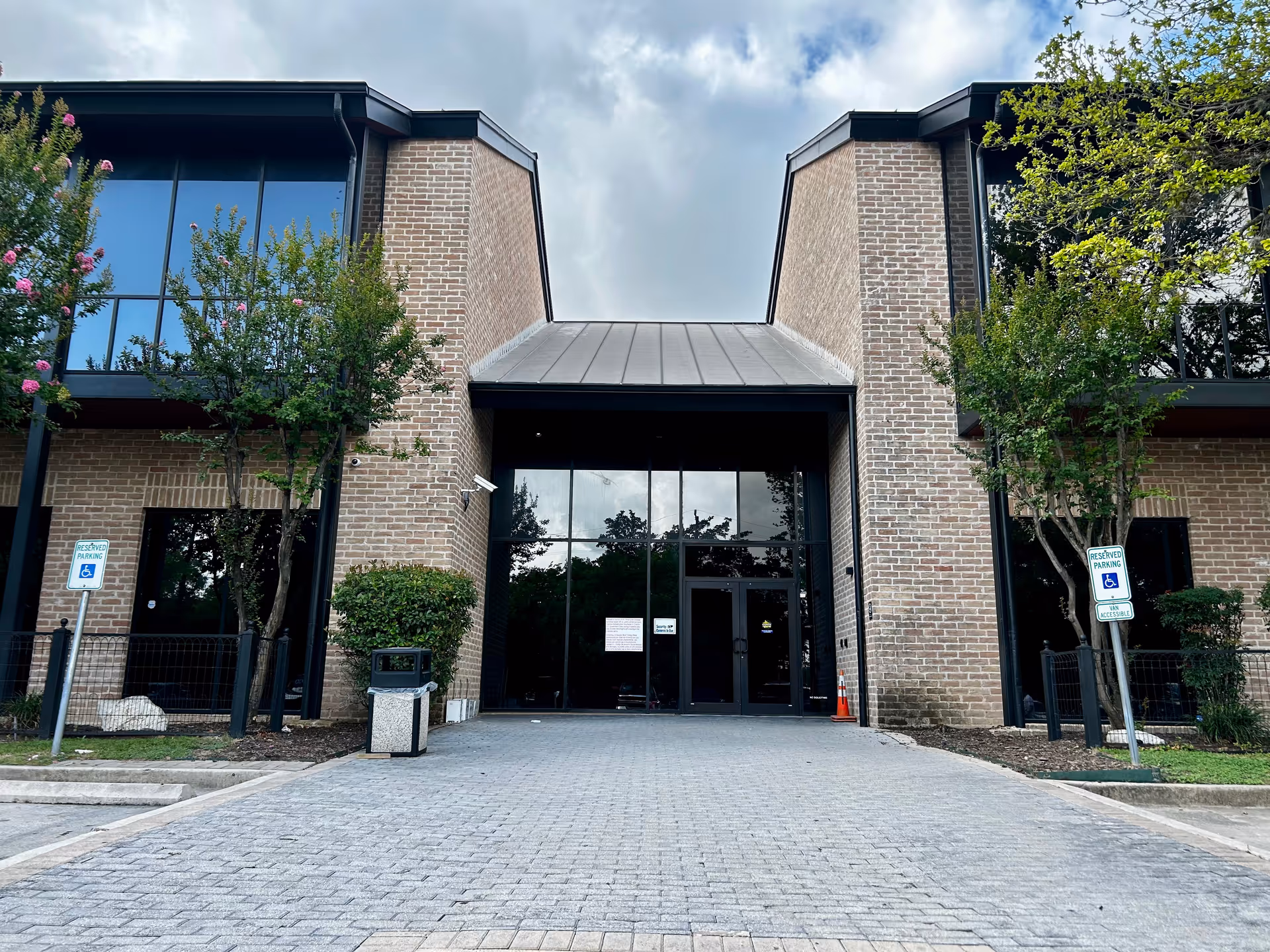 Modern brick senior care facility exterior with glass entrance and landscaped trees.