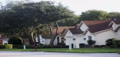 Exterior view of Wellington at Seven Hills residential buildings with white walls and green landscaping.