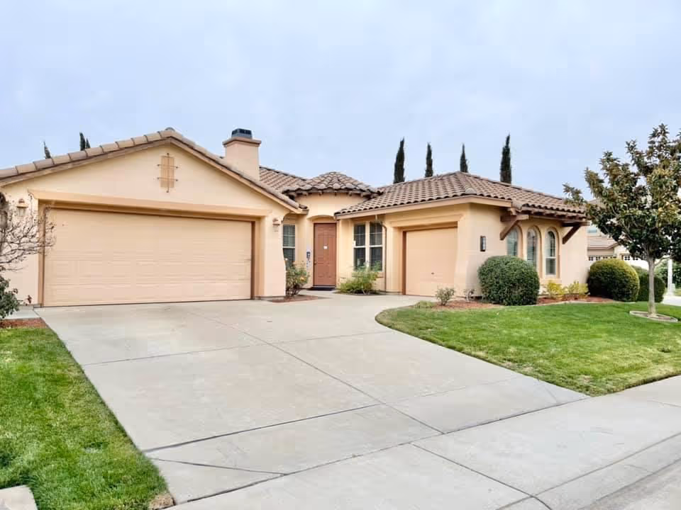 Tan, single-story senior care home with two-car garage and manicured lawn.