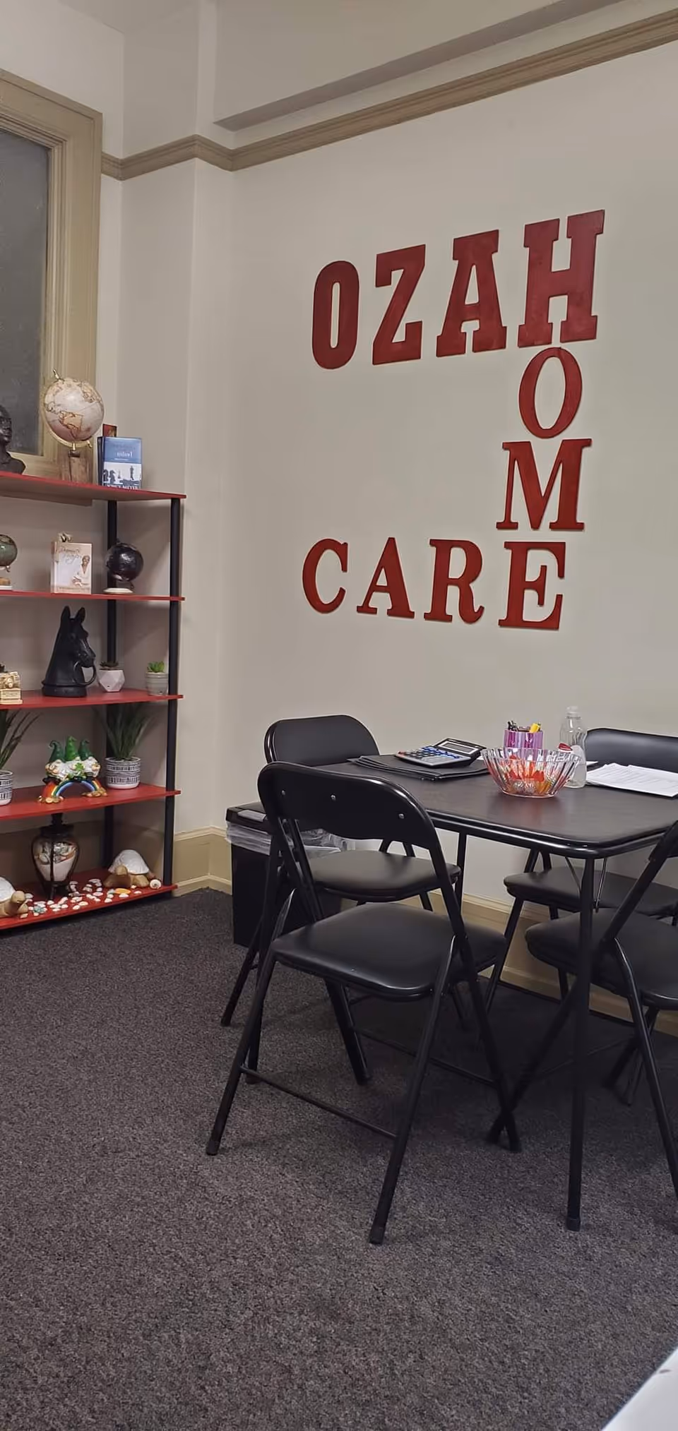 Interior lounge area with a table, folding chairs, and a shelf against a wall.
