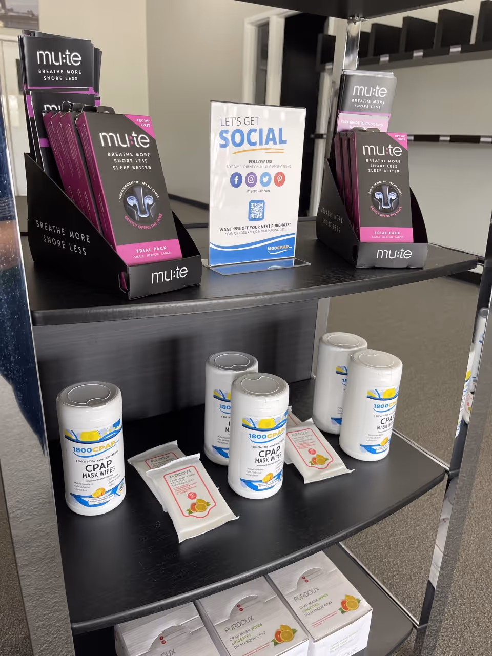 Shelf display of CPAP masks, wipes, and related supplies in a facility corridor.