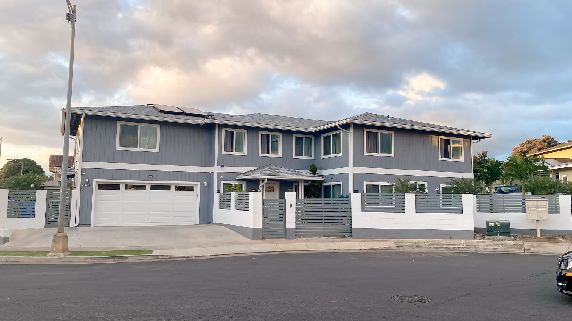 Two-story gray care home building with a gated front entrance and driveway.
