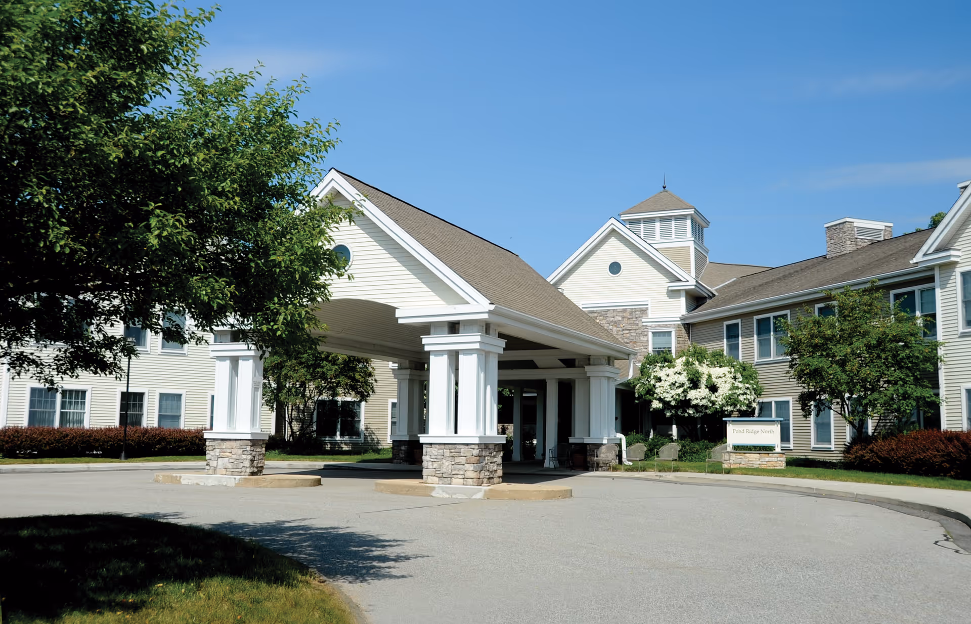A senior living facility entrance with a porte-cochère and landscaped driveway.