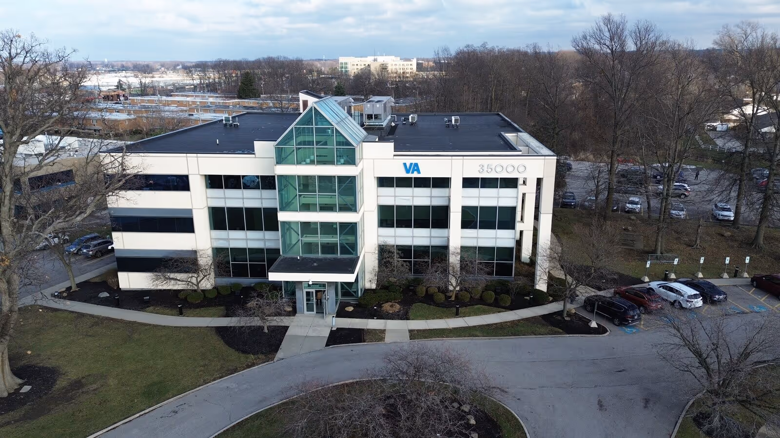 Aerial view of a modern glass front building with a curved driveway and trees