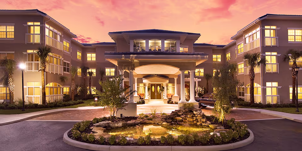 Evening view of The Residence at Timber Pines front entrance with landscaped roundabout fountain.