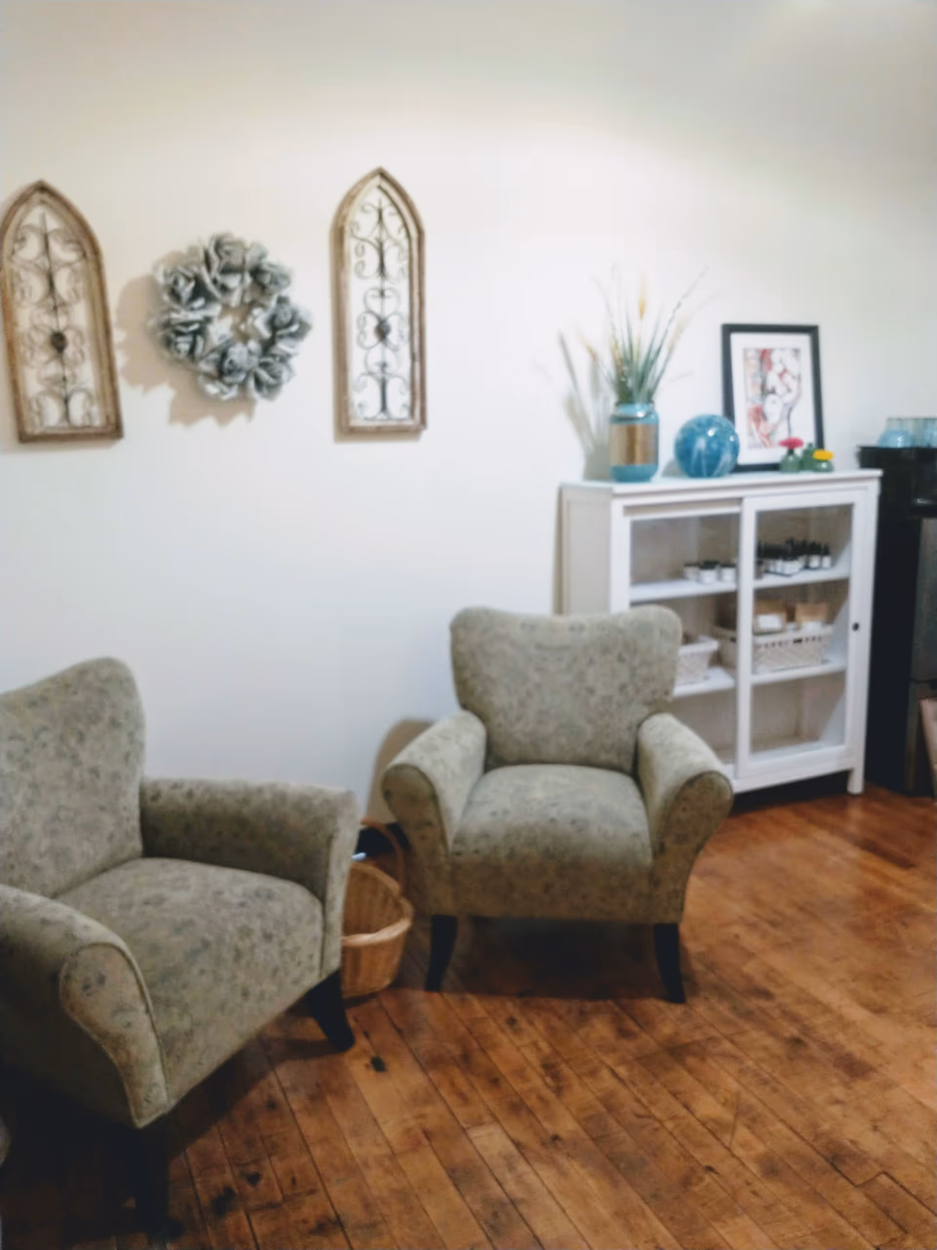 Two patterned armchairs sit in a cozy living room with a white cabinet and decor.