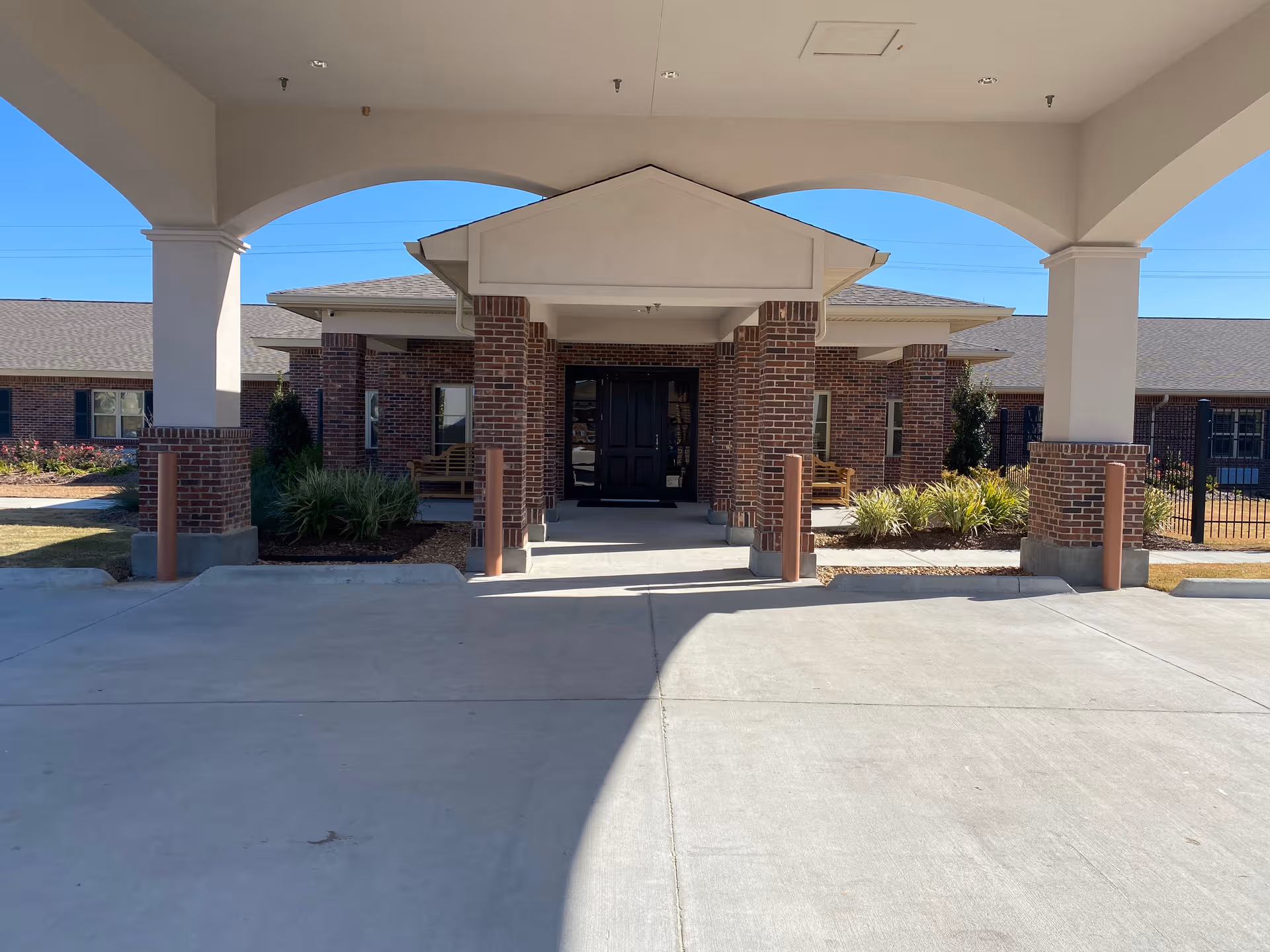 Front entrance of a brick senior living facility under a covered porte-cochere.