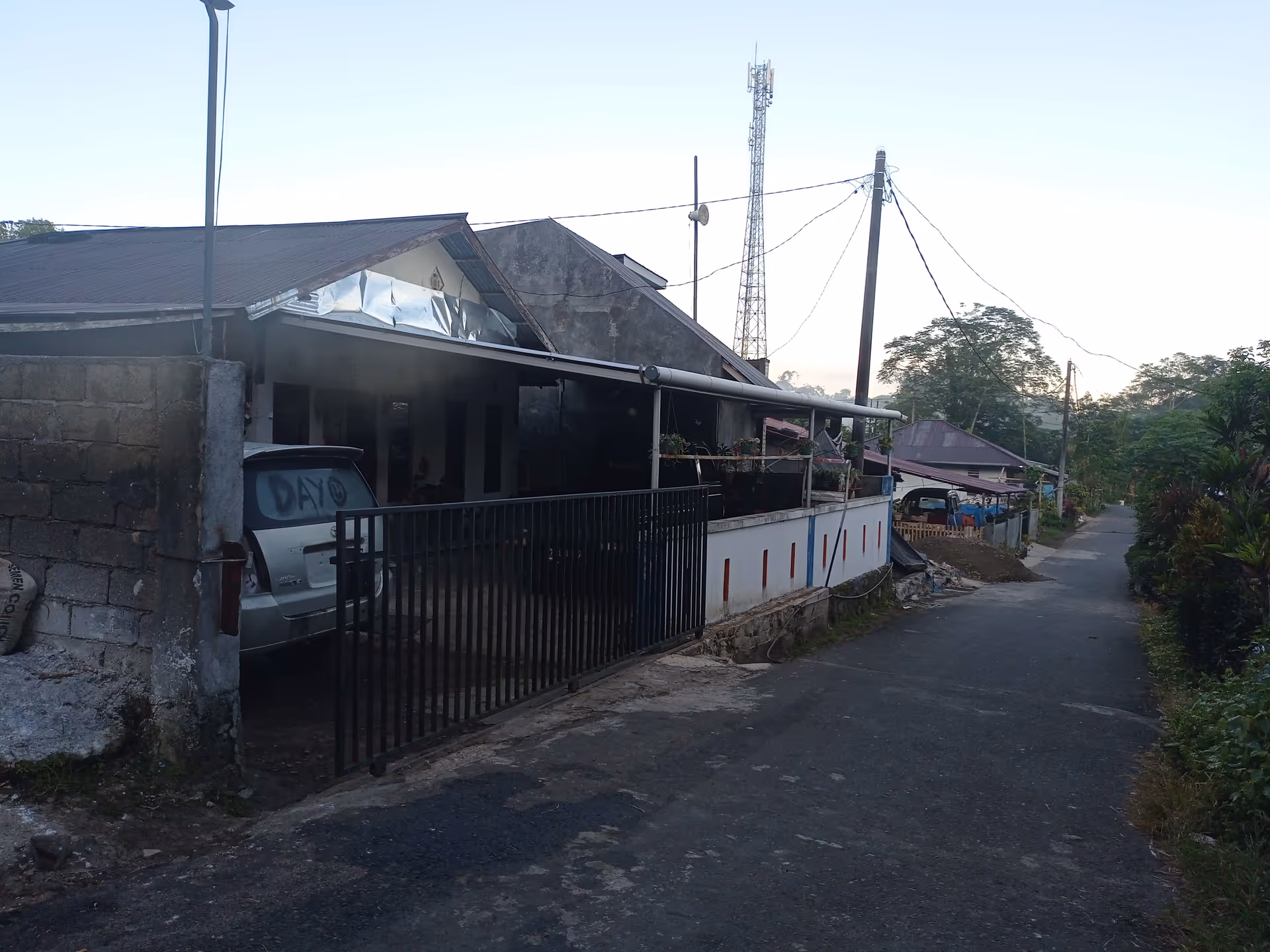 Gated, single-story building along a street with a parked car.