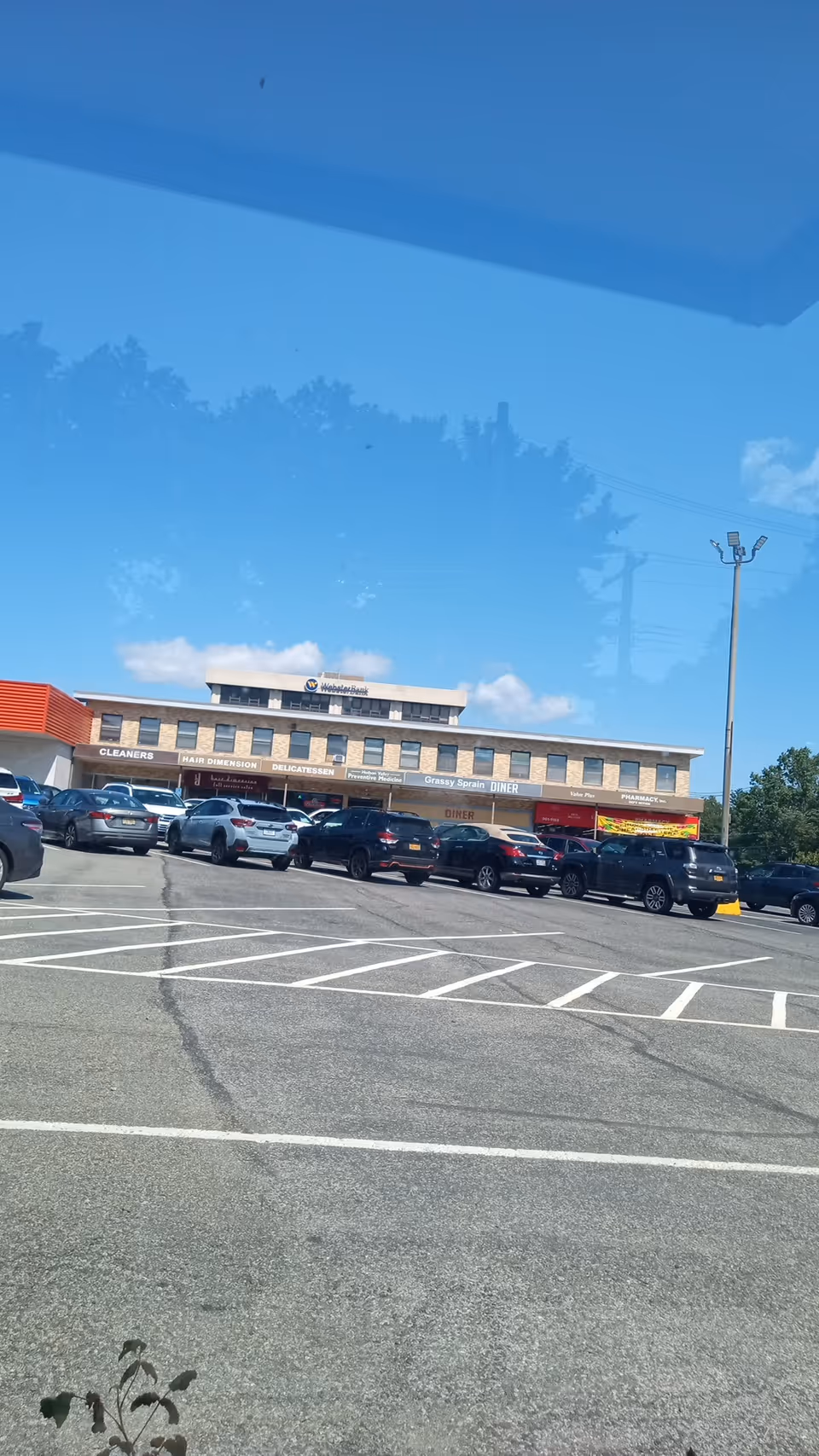 Exterior view of Bestcare Inc facility with a parking lot and storefronts.