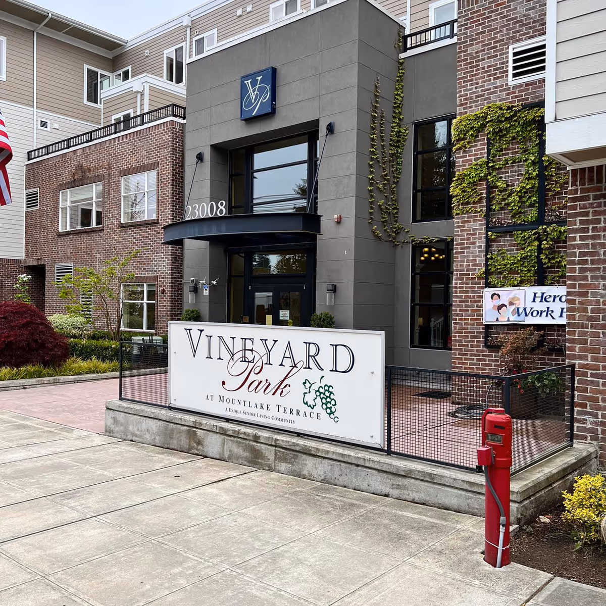 Modern, multi-story senior living building entrance with Vineyard Park sign in Mountlake Terrace