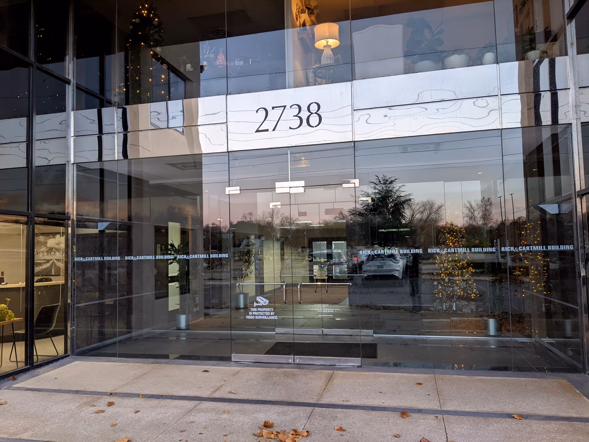 Glass-front building entrance with large 2738 address and reflected trees.