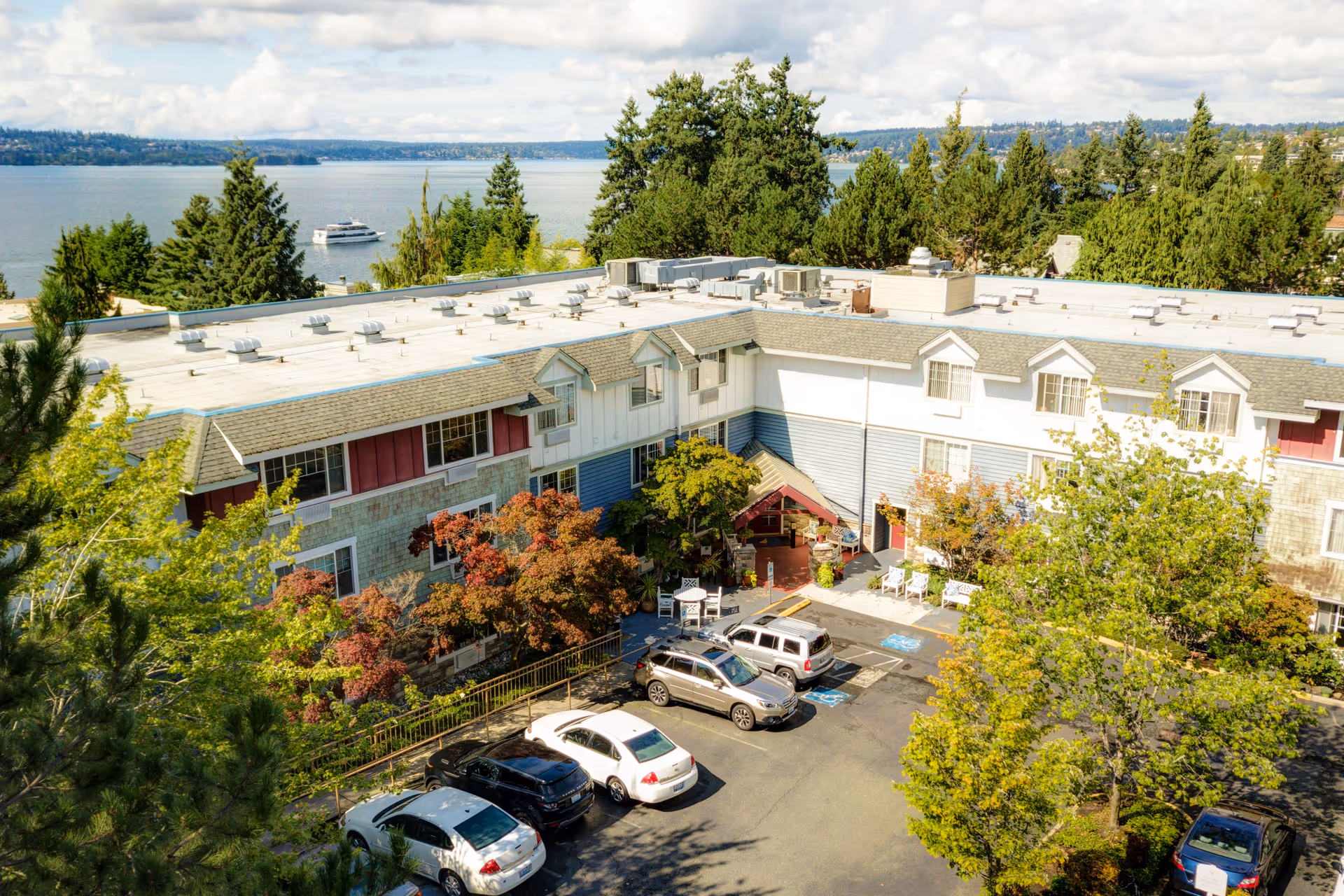 Aerial view of a COGIR Senior Living building with parked cars and trees.