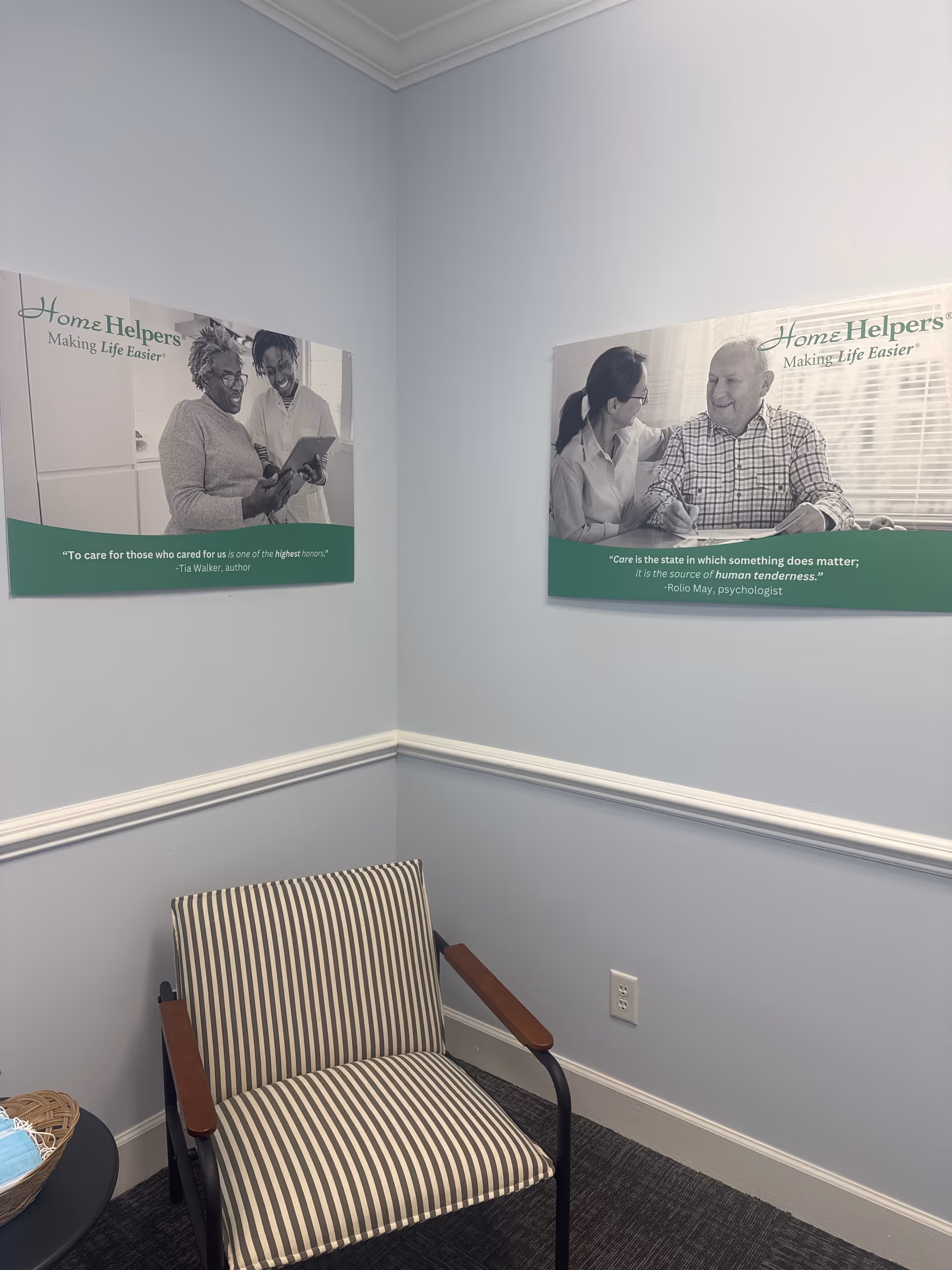 Corner waiting area with striped chair and two posters on light blue walls.