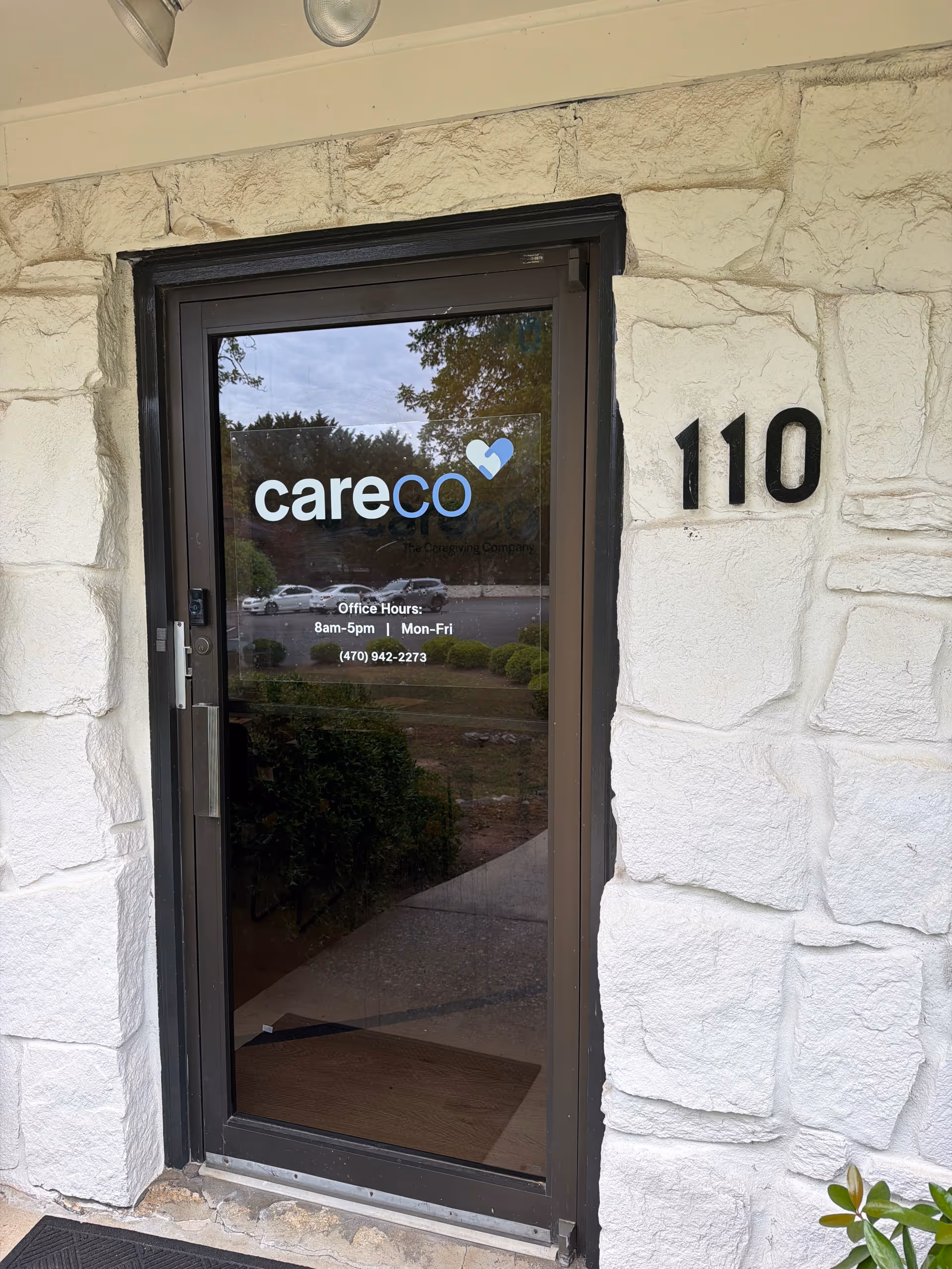 Glass door entrance with CareCo sign and building number 110 on stone facade.