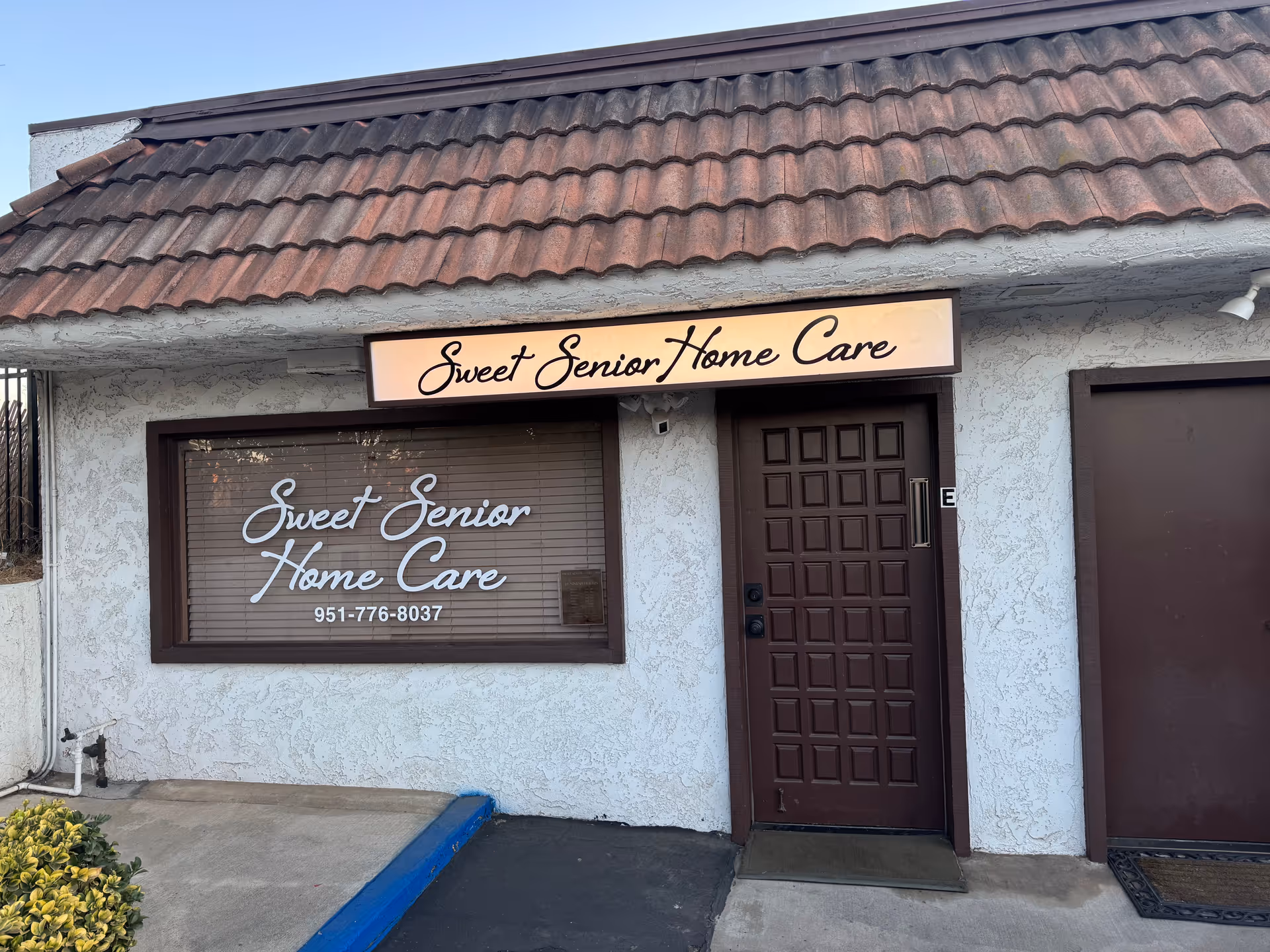 Exterior view of Sweet Senior Home Care facility with sign and front door.