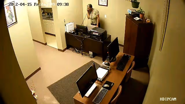 Indoor reception area with a staff member at a desk and computers.