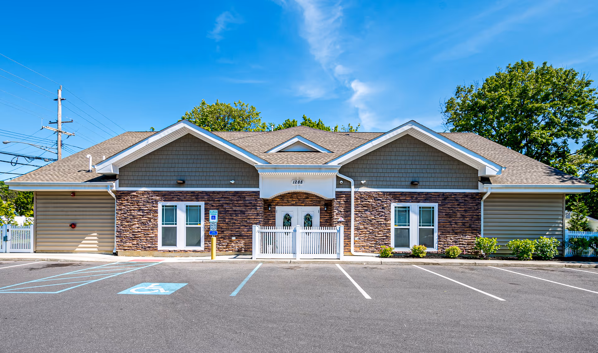 Front view of a single-story senior living facility with stone facade and parking lot.