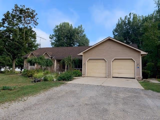 A single-story facility exterior with beige siding, a two-car garage, and a gravel driveway.