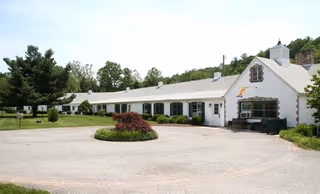Front view of Highland House, a single-story white retirement home with a circular driveway.