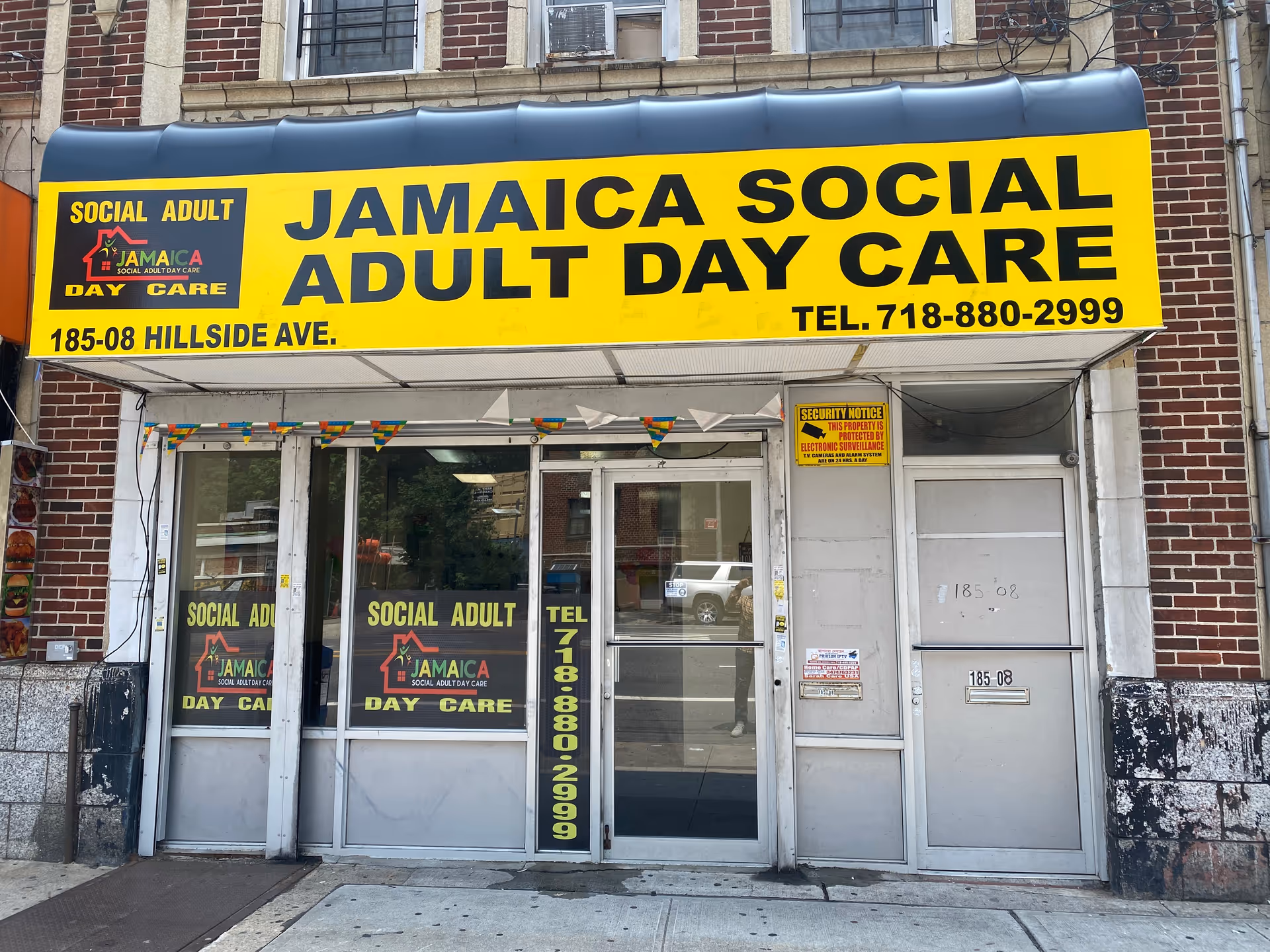 Bright yellow Jamaica Social Adult Day Care storefront sign above glass doors.