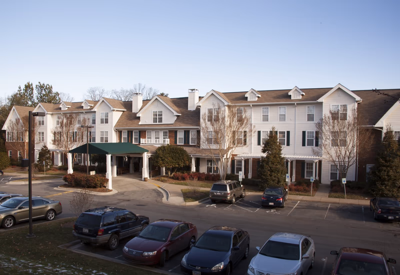 Exterior view of Brighton Gardens of Winston-Salem with parked cars and entrance.